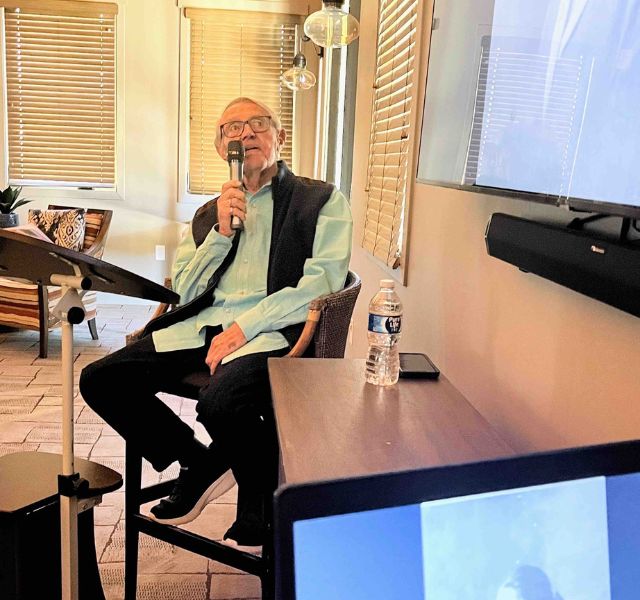 Person sitting on a stool talking into a microphone.