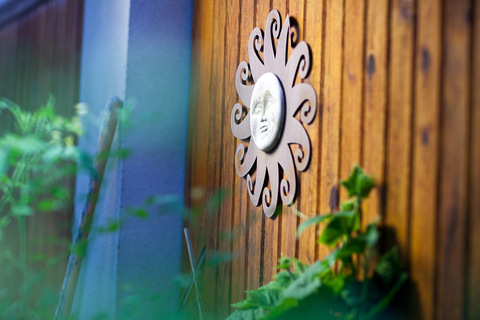 A metal sun sculpture hanging on an exterior wall.