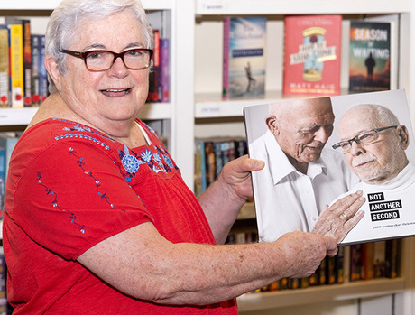 A resident is holding open a book in the library.