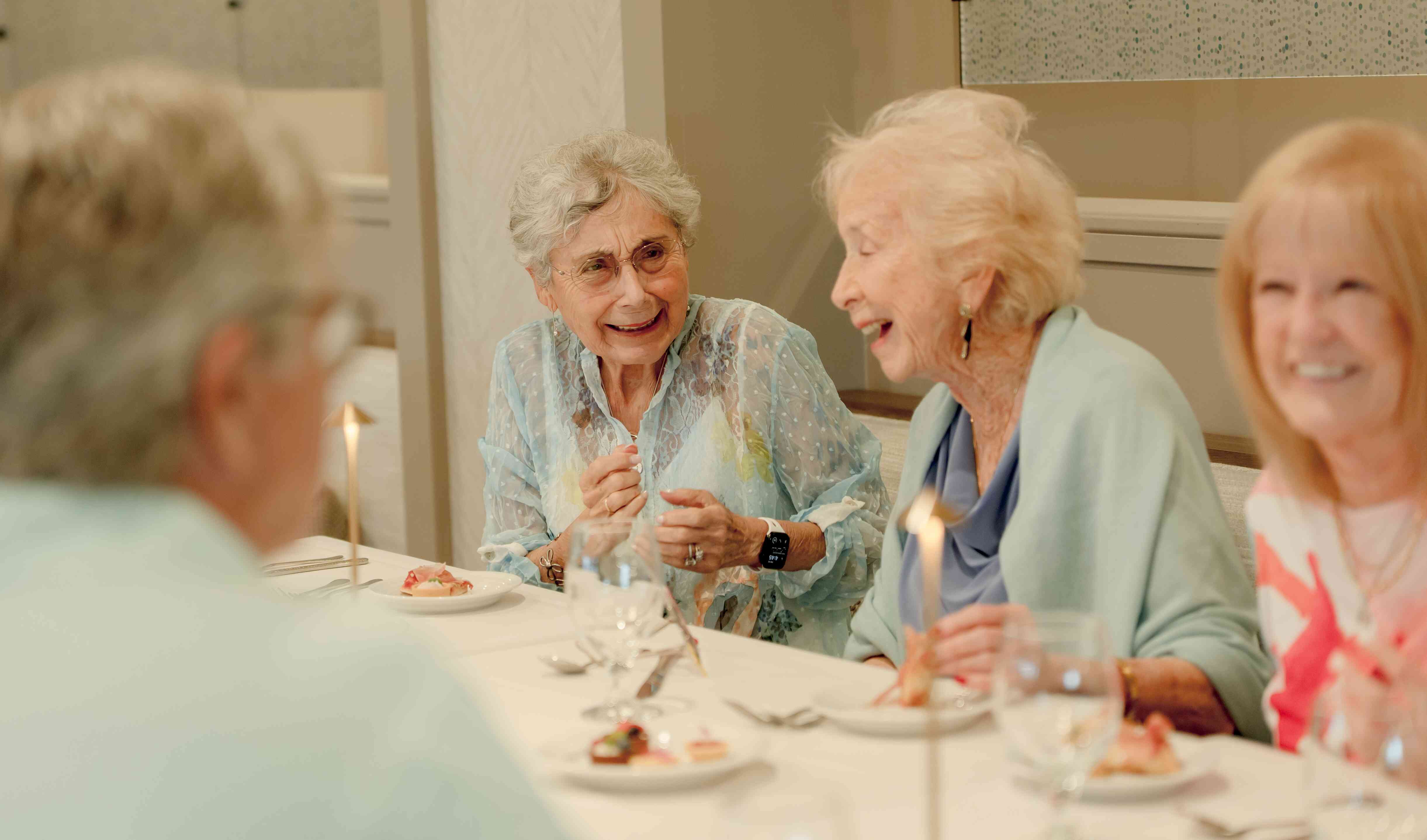 Three residents laughing while enjoying dinner.