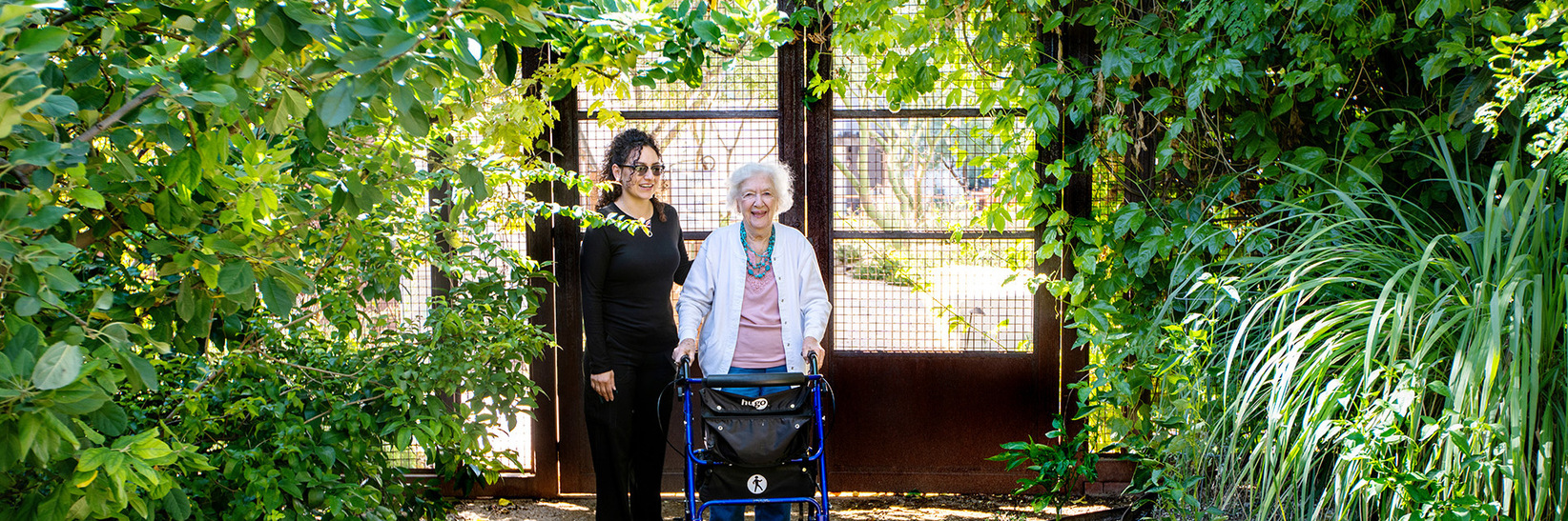 A resident with their caregiver outside The Hacienda at The River, a memory care community in Tucson. A resident with their caregiver outside The Hacienda at The River, a memory care community in Tucson.