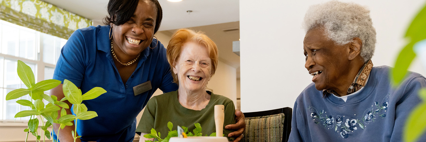 A caregiver laughing with residents at Blue Bell Place Memory Care community in Blue Bell.