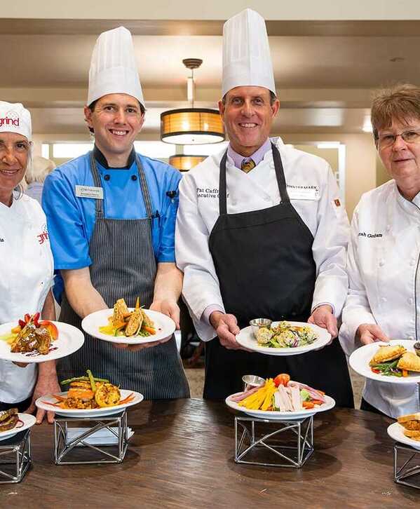 Nourish Watermark Community chefs displaying a variety of meals they have prepared on-site for residents