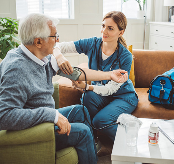 A nurse taking a person's blood pressure at home.