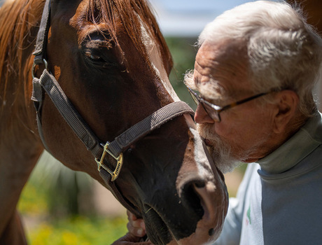 A resident kissing a horse.