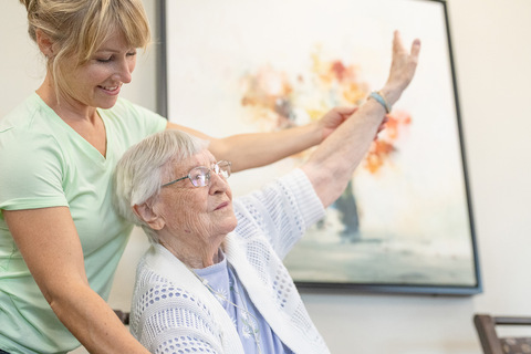 A caregiver helps a resident stretch their arm.