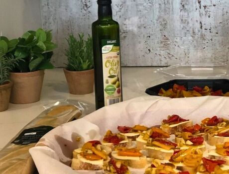 A dish of sliced baguette with cheese, tomato, and olive oil on top.
