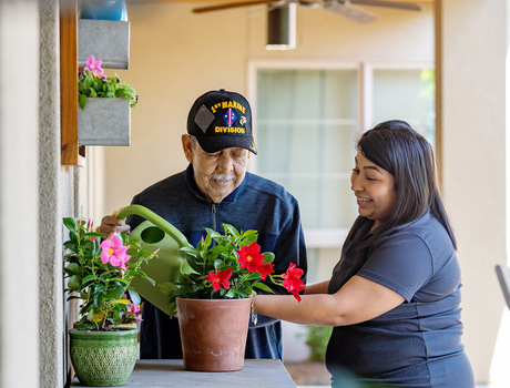 A caregiver helping a person water plants.