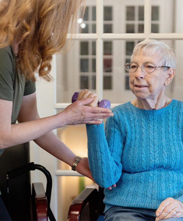 Accordion image A person helping a resident with a weight.