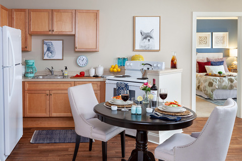 Furnished kitchen with table, cabinets, and refrigerator.