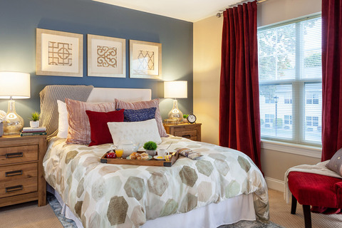 Furnished bedroom with bed, drawers, and soft lighting.
