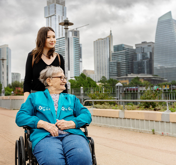 A person in a wheelchair with another in the city.