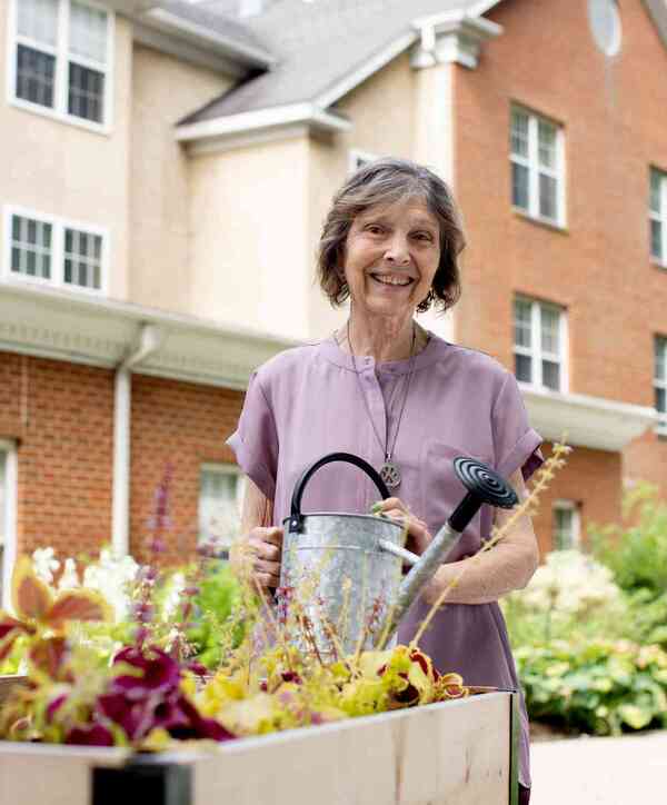 Accordion image Resident holding a watering can and watering plants.