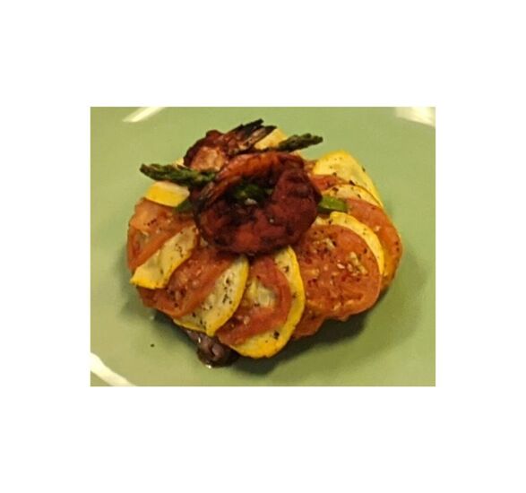 A surf and turf dish with shrimp, asparagus, and tomatoes.