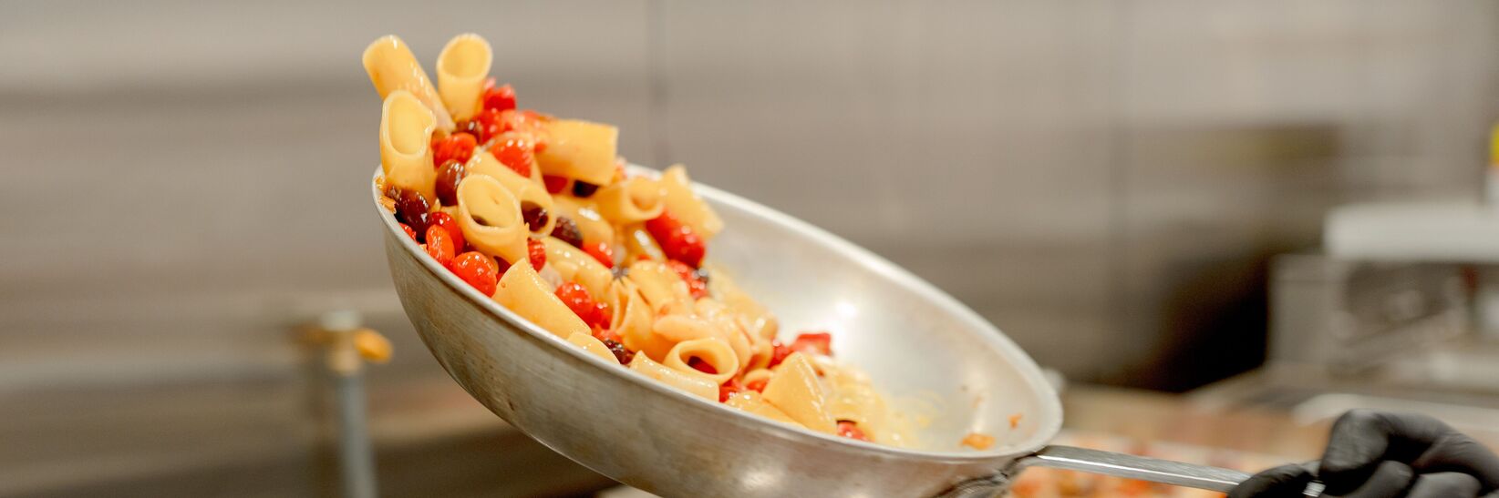 Pasta being tossed in a pan on a stovetop. Pasta being tossed in a pan on a stovetop.