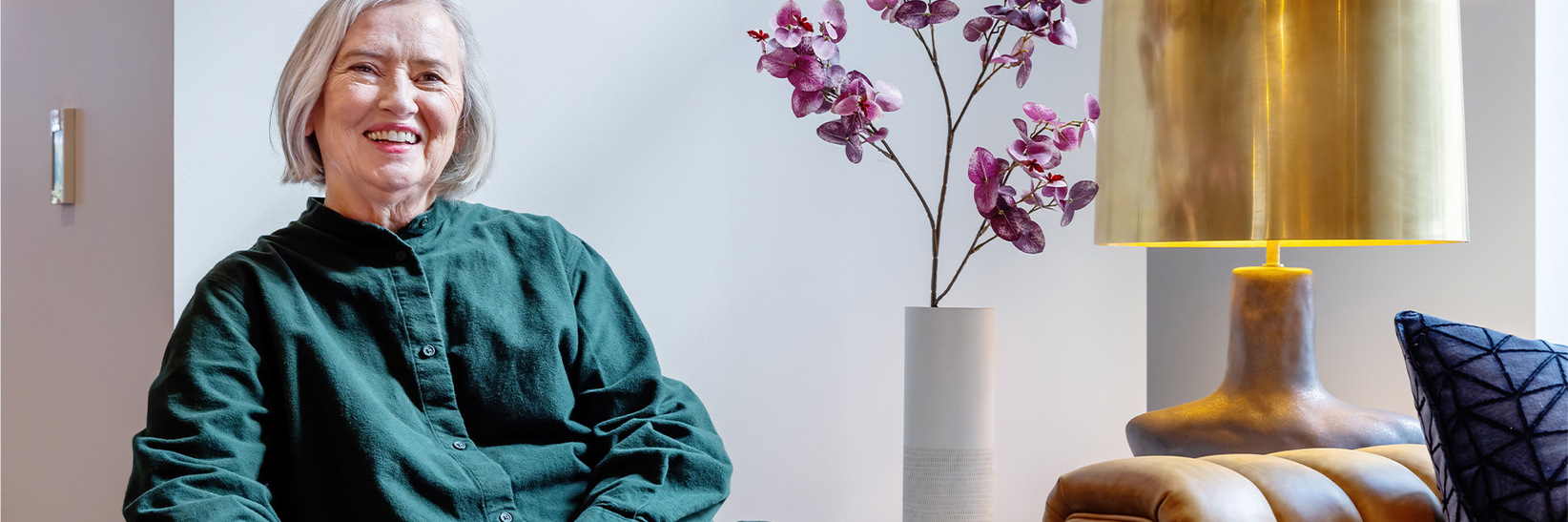 A person sitting on the couch, smiling at The Watermark at Bellevue senior living community.