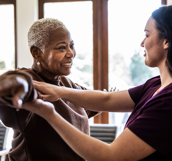 A caregiver helps a resident stretch their arm. 