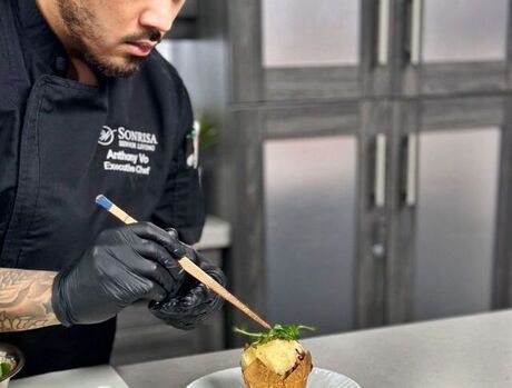 A chef finishing a dish in the kitchen.