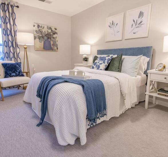 A fully furnished bedroom with white comforter and blue throw at end of bed.