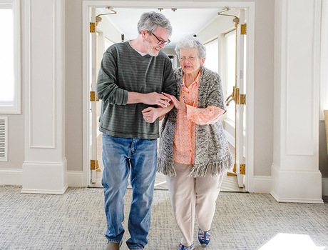 A person assisting a resident walking.