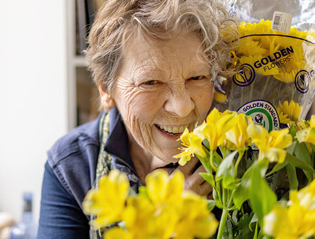 A person smiling with a bouquet of flowers.
