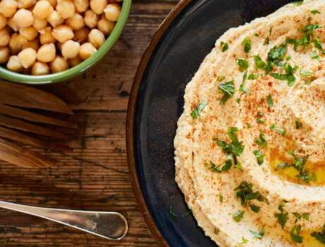 A bowl of hummus next to a bowl of chickpeas.