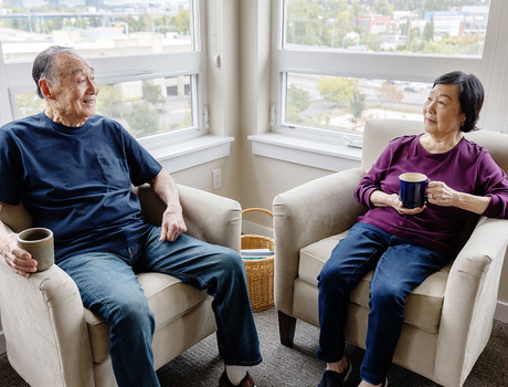 Two people sitting by the window drinking coffee.