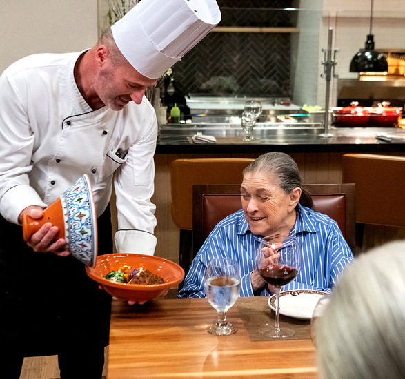 A chef is showing a dish to a resident.