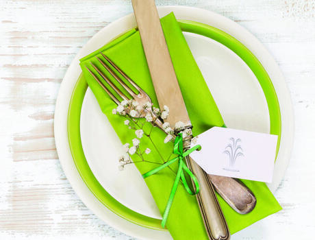Table setting with white and green plates and silverware.
