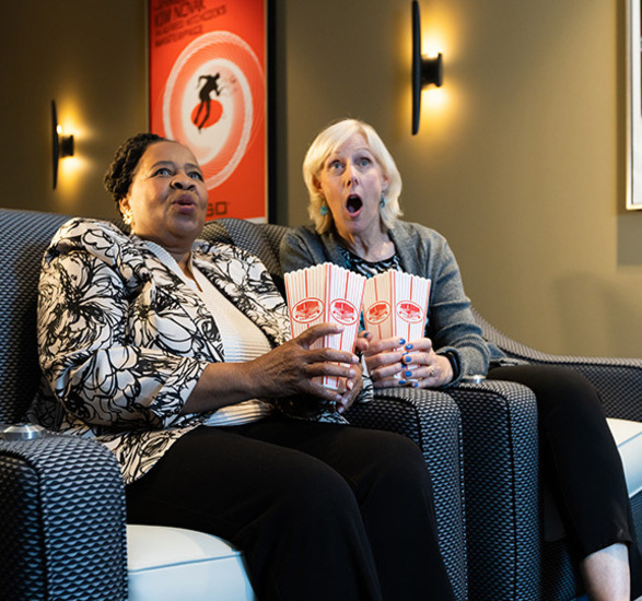 Two people in a theater reacting to a movie.