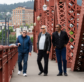 Three people walking across a bridge near Portland.