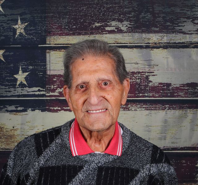 Man smiling in front of painting of American Flag