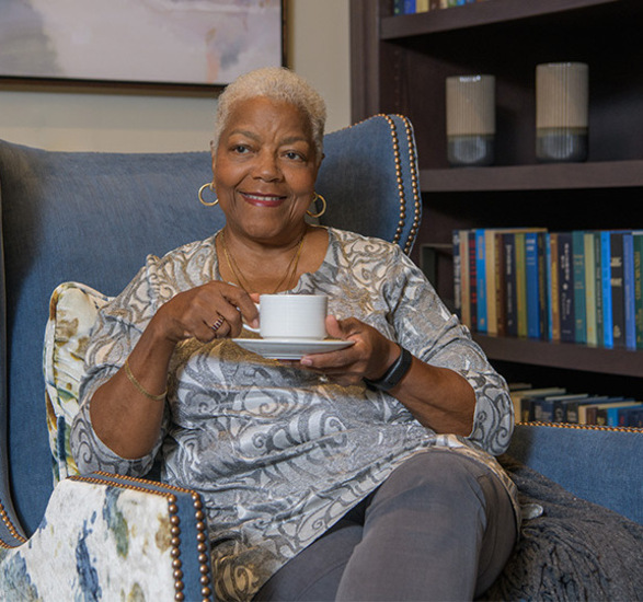 A resident sitting in the library with coffee.