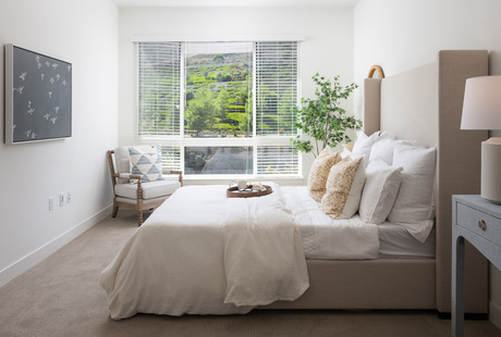 A fully furnished bedroom with a large window.