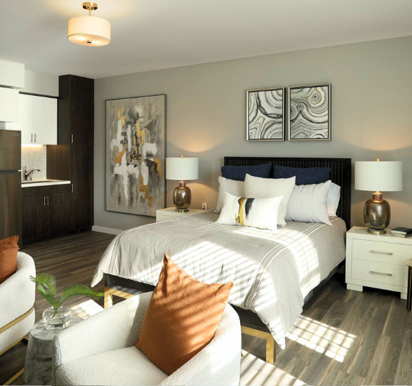 Studio apartment with bed, kitchenette, and chairs