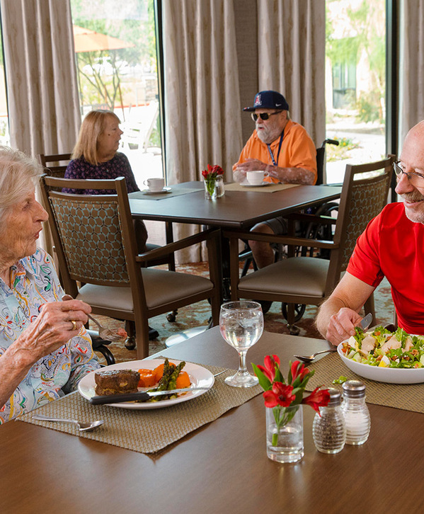 Accordion image Two residents are sitting at a dining table enjoying a meal together.