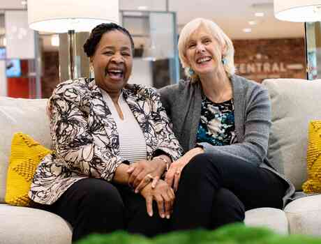 Two residents sitting on a couch and laughing.