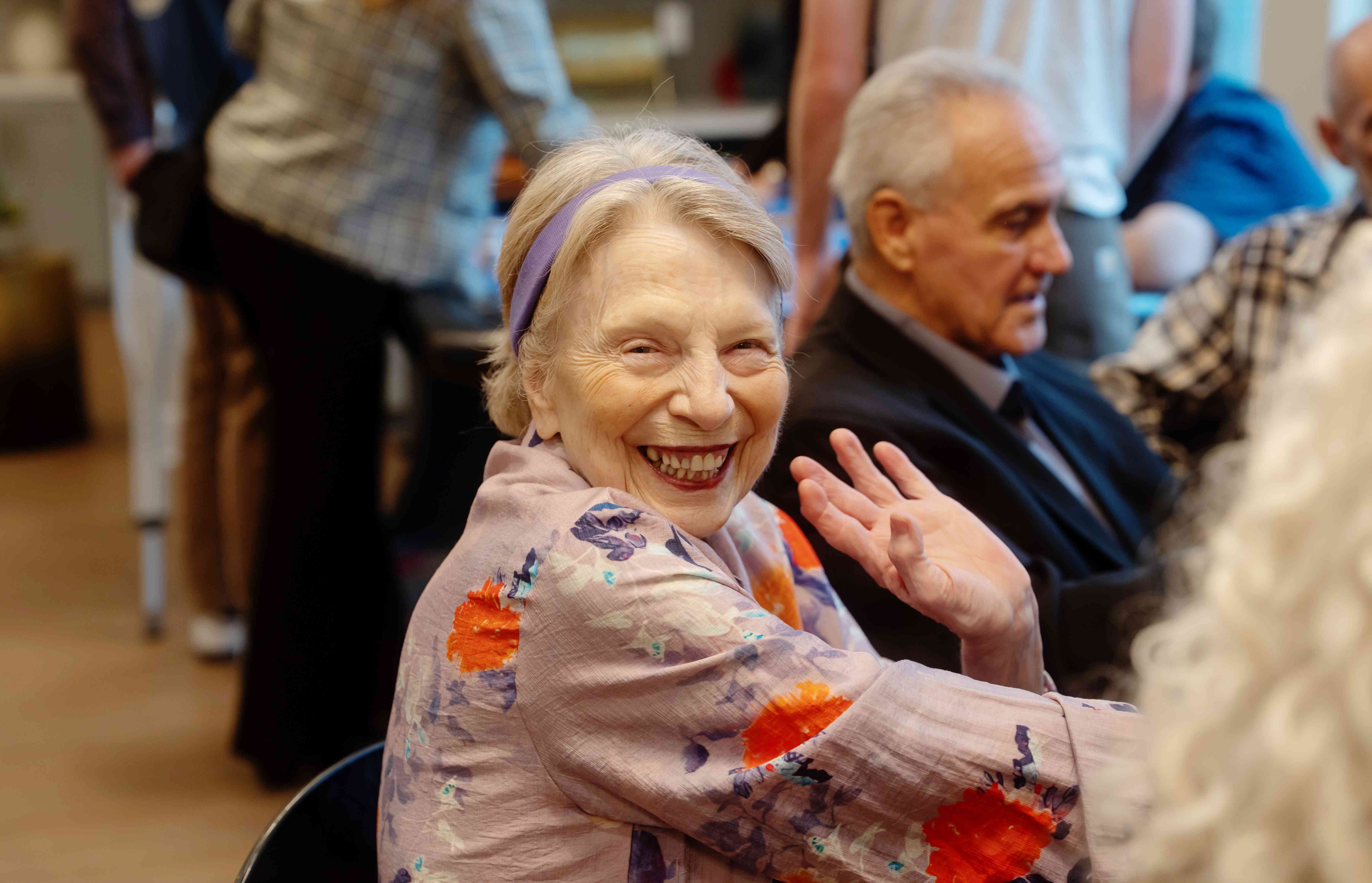 Resident smiling and waving at the camera while at an event.