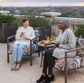 Two women sitting on the rooftop having drinks.