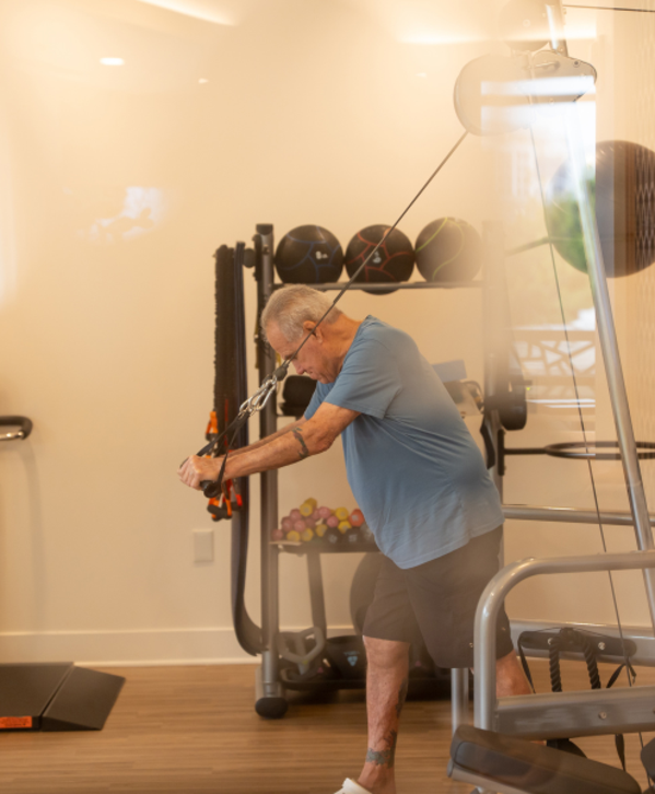 Resident standing and using weights in fitness center.