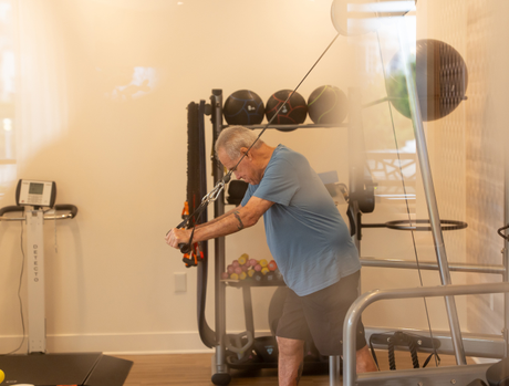 Resident standing and using weights in fitness center.