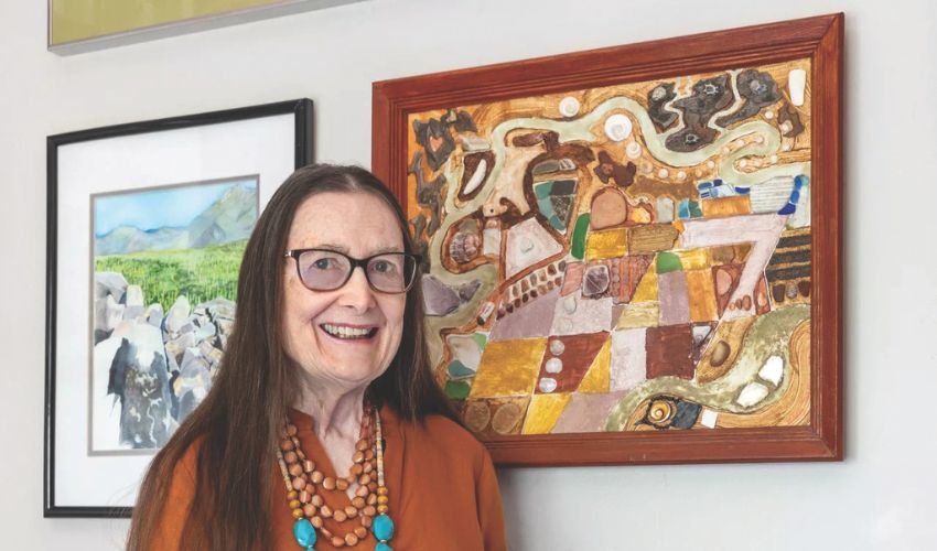 A resident and retired artist standing in front of art work.