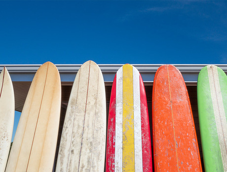A bunch of surf boards standing up.