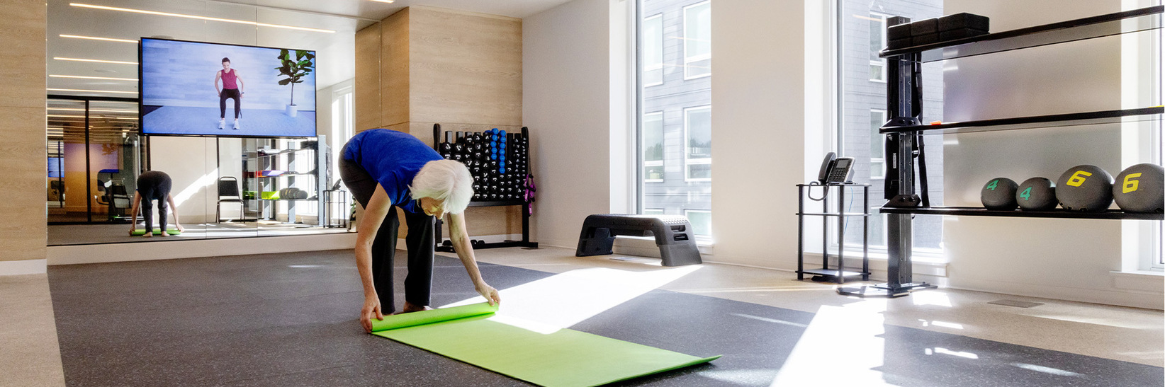 A person rolling out a yoga mat. A person rolling out a yoga mat.