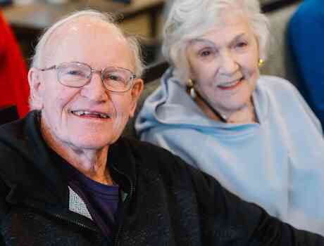 Two residents sit side by side, smiling warmly during a social gathering.