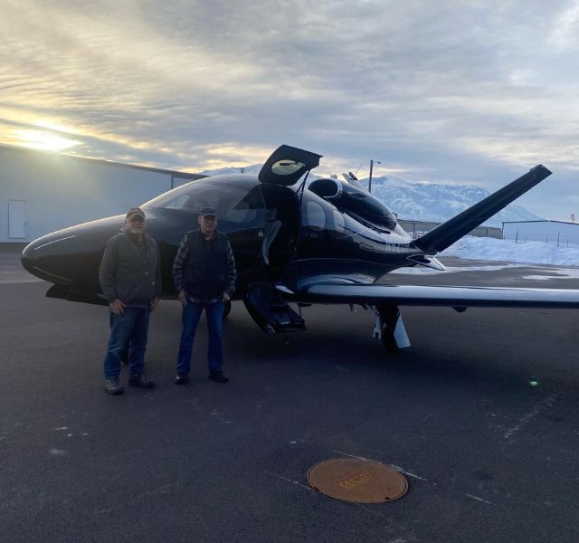 Two people standing outside of fighter plane.
