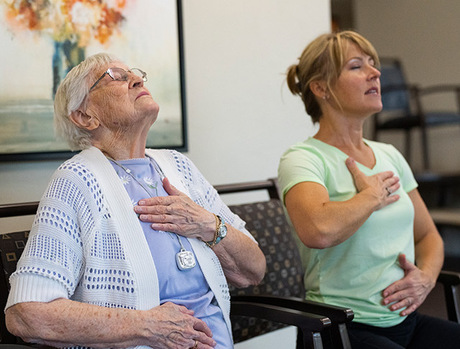 A resident is working on a breathing exercise with an associate.