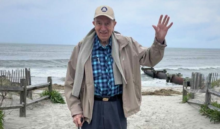 A resident is at a beach and waving.
