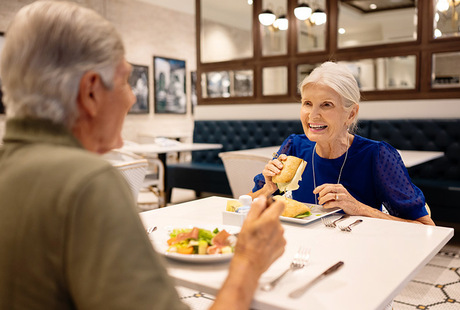 Two people having lunch in the cafe at the Watermark Laguna Niguel senior living community.