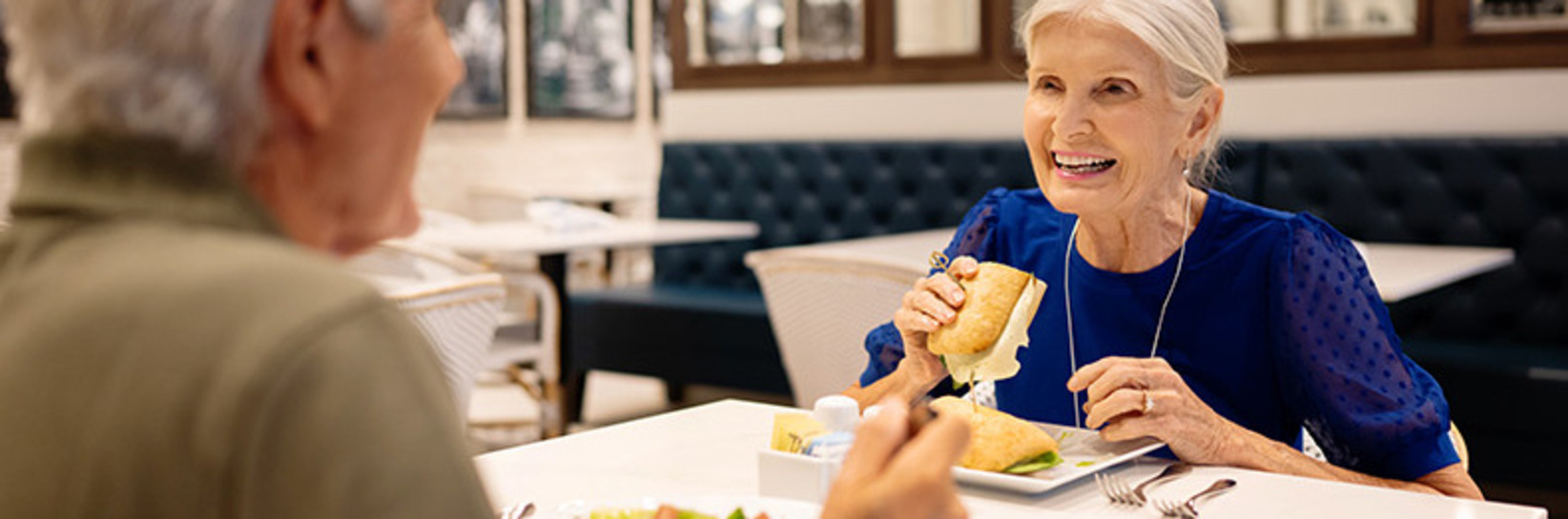 Two people having lunch in the cafe at the Watermark Laguna Niguel senior living community.